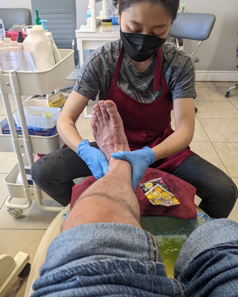A Queen's Nails technician in mask and gloves giving a pedicure foot massage